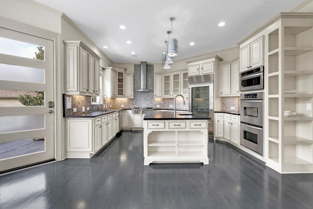 kitchen featuring sink, wall chimney range hood, pendant lighting, decorative backsplash, and appliances with stainless steel finishes