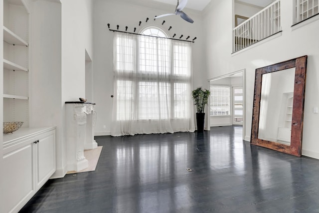 unfurnished living room with plenty of natural light, dark hardwood / wood-style floors, and a high ceiling