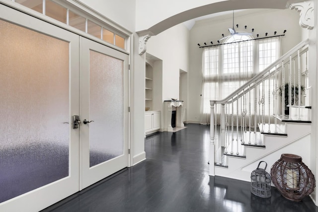 foyer entrance with french doors, a towering ceiling, ceiling fan, and dark wood-type flooring