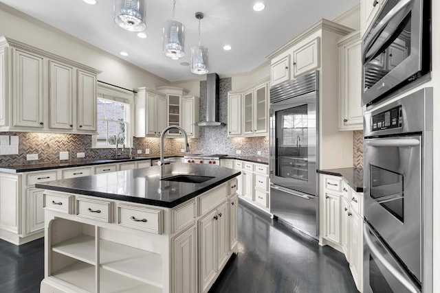 kitchen featuring pendant lighting, wall chimney range hood, appliances with stainless steel finishes, tasteful backsplash, and a kitchen island