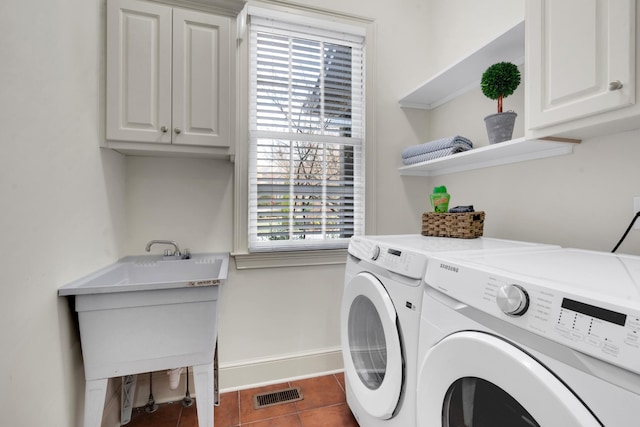 clothes washing area featuring cabinets, separate washer and dryer, dark tile patterned floors, and a healthy amount of sunlight