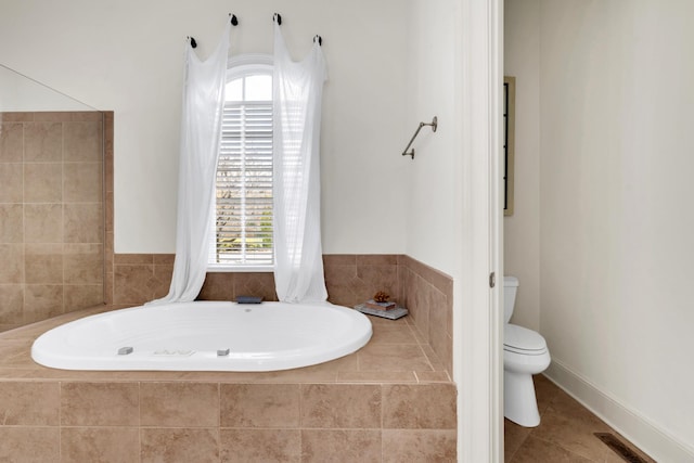 bathroom featuring tile patterned floors, tiled bath, and toilet