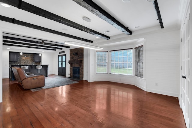 unfurnished living room with beamed ceiling, dark hardwood / wood-style flooring, and a fireplace