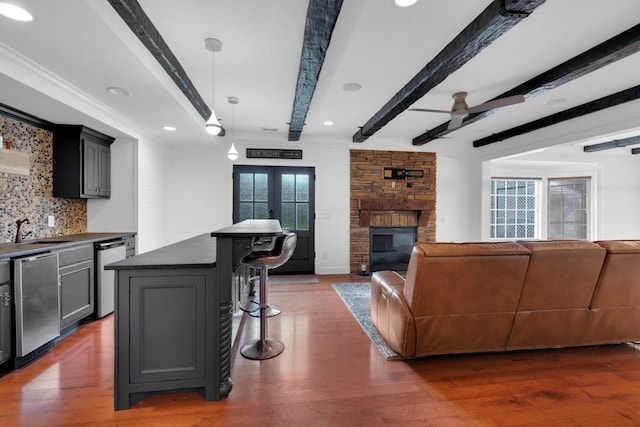 living room featuring beam ceiling, sink, and hardwood / wood-style flooring