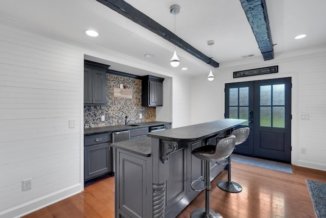 kitchen with beam ceiling, french doors, dark hardwood / wood-style flooring, decorative light fixtures, and a kitchen bar