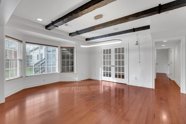 spare room with beam ceiling, wood-type flooring, and french doors