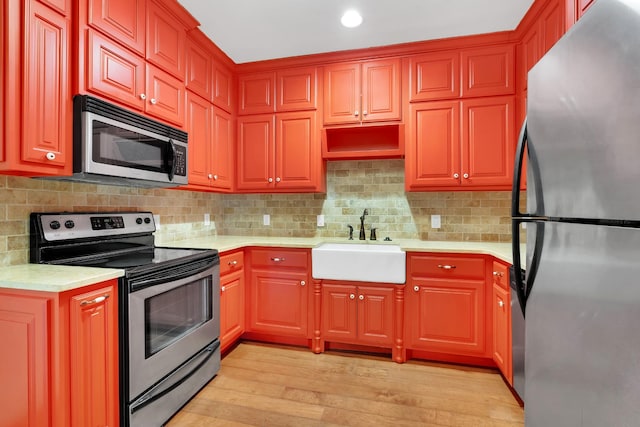 kitchen featuring tasteful backsplash, sink, light hardwood / wood-style flooring, and appliances with stainless steel finishes