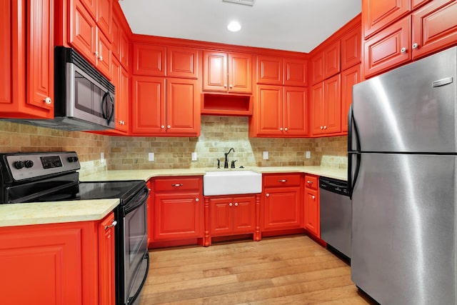 kitchen featuring decorative backsplash, appliances with stainless steel finishes, light hardwood / wood-style floors, and sink