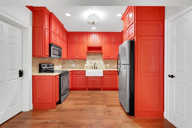 kitchen featuring tasteful backsplash, sink, appliances with stainless steel finishes, and light hardwood / wood-style flooring