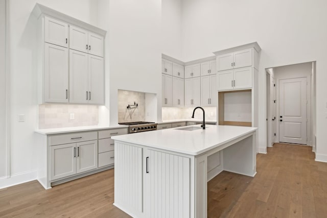 517 Matthew Miller Dr, Smyrna, TN 37167 - kitchen with a high ceiling, light wood-type flooring, decorative backsplash, light countertops, and a center island with sink