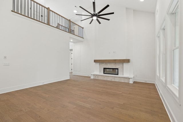 517 Matthew Miller Dr, Smyrna, TN 37167 - unfurnished living room with a high ceiling, a ceiling fan, a glass covered fireplace, wood finished floors, and recessed lighting