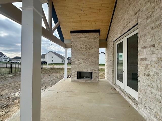 view of patio / terrace with french doors, fence, and an outdoor fireplace