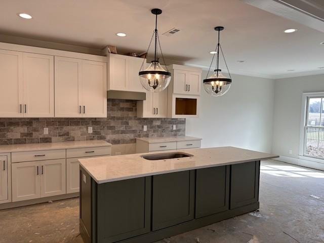 kitchen with white cabinets, decorative light fixtures, and an island with sink