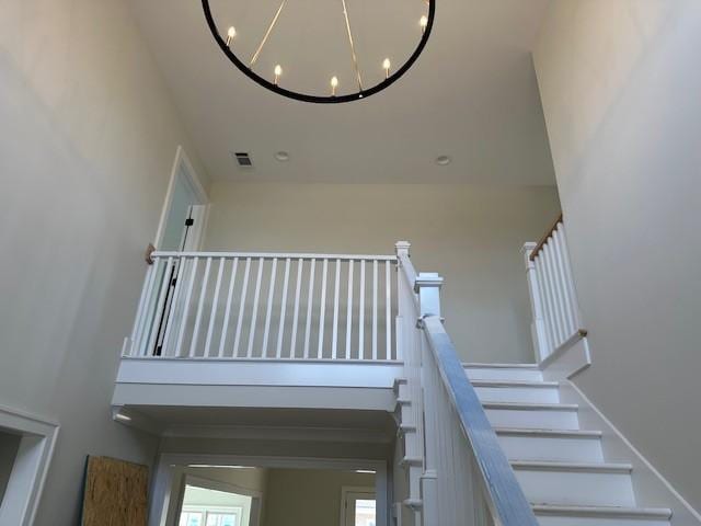 staircase featuring a high ceiling, visible vents, and a chandelier