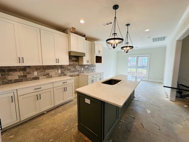 kitchen with visible vents, a kitchen island, decorative light fixtures, white cabinetry, and backsplash