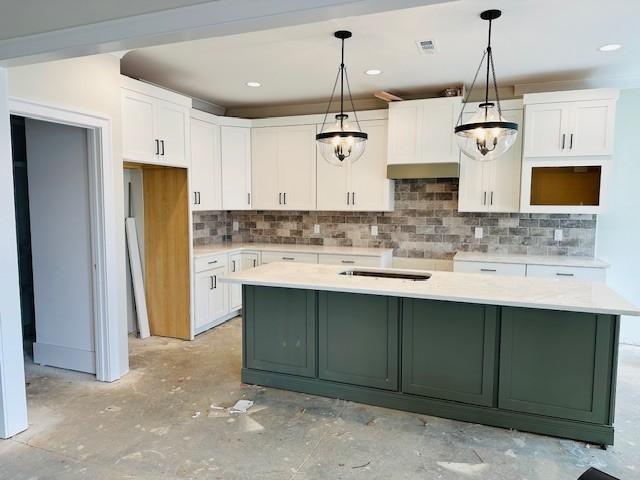 kitchen featuring light countertops, a kitchen island, white cabinetry, and decorative light fixtures