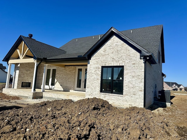 back of house featuring a shingled roof, a patio area, and brick siding