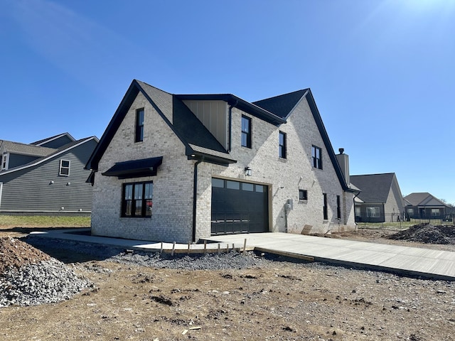 view of side of property featuring a garage, concrete driveway, and brick siding