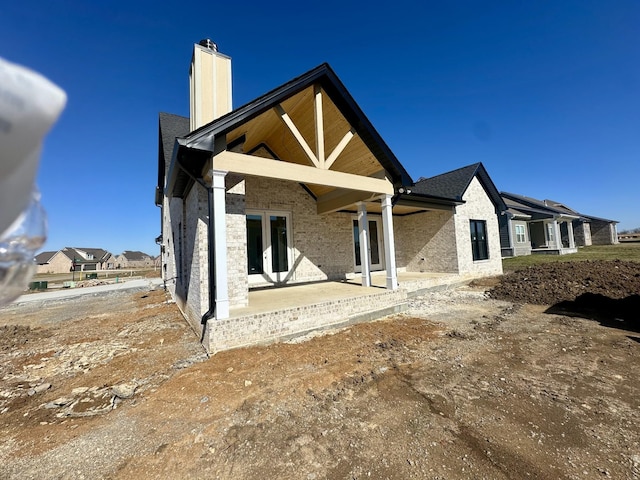 rear view of property with a residential view, french doors, a patio area, and a chimney