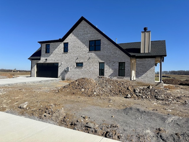 view of property exterior featuring a garage, concrete driveway, a chimney, roof with shingles, and brick siding