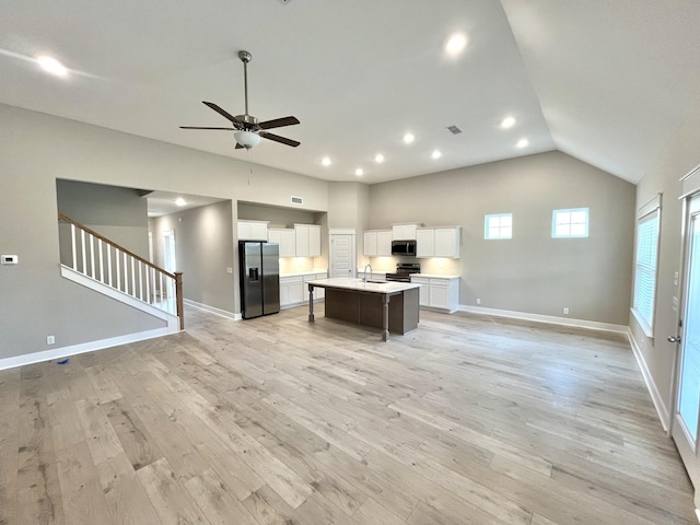 kitchen with light hardwood / wood-style flooring, a kitchen breakfast bar, an island with sink, stainless steel appliances, and white cabinets