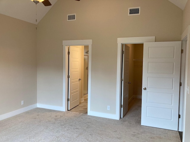 unfurnished bedroom with a spacious closet, high vaulted ceiling, light carpet, a closet, and ceiling fan