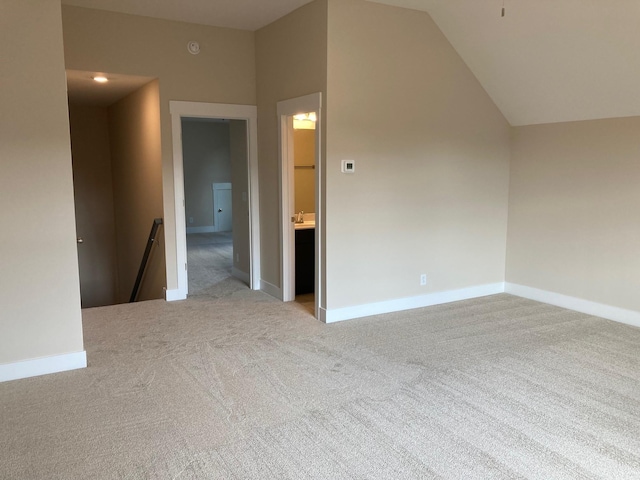 additional living space with light colored carpet and vaulted ceiling