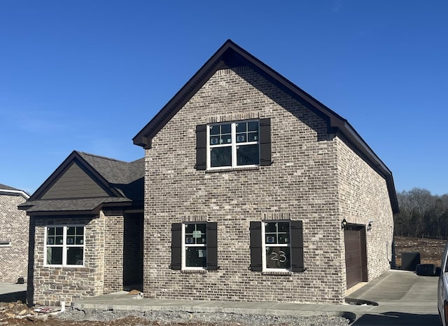 view of front of house with a garage, a shingled roof, central AC unit, and brick siding