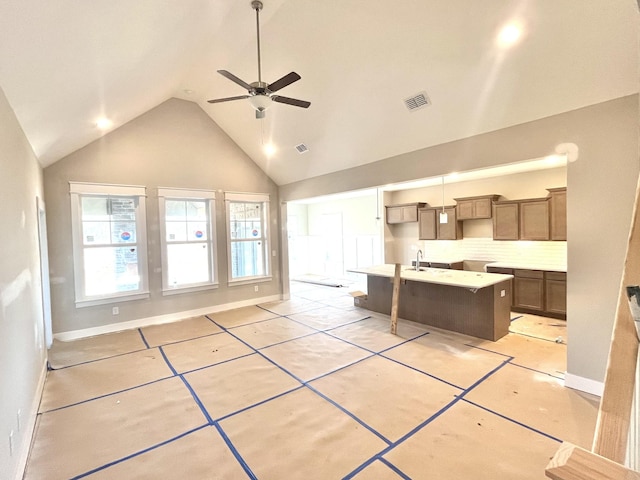 kitchen featuring visible vents, decorative backsplash, baseboards, a kitchen island, and high vaulted ceiling