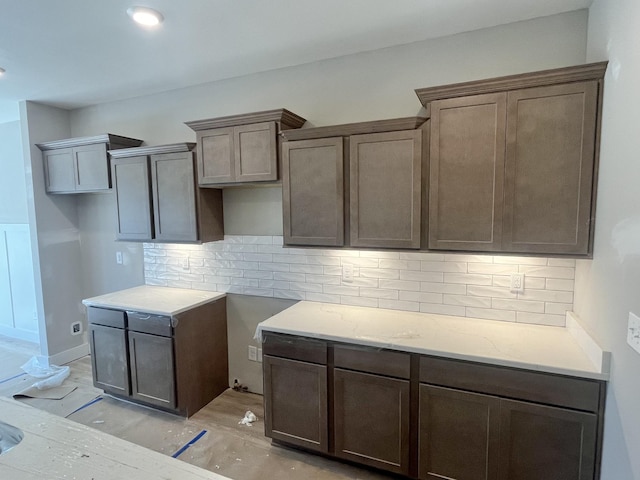 kitchen with light wood finished floors, backsplash, and light stone countertops