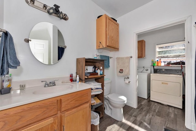 bathroom with hardwood / wood-style floors, vanity, toilet, and washing machine and clothes dryer