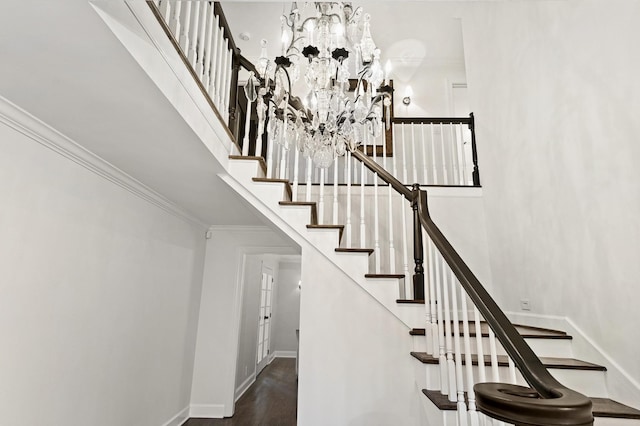 staircase with wood-type flooring, crown molding, and a chandelier