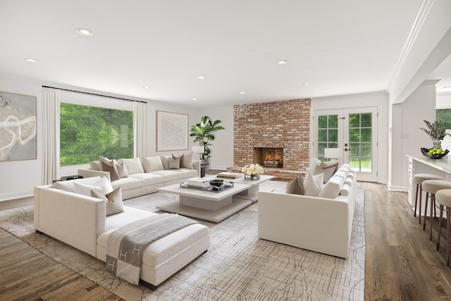 living room featuring a fireplace, crown molding, hardwood / wood-style floors, and french doors