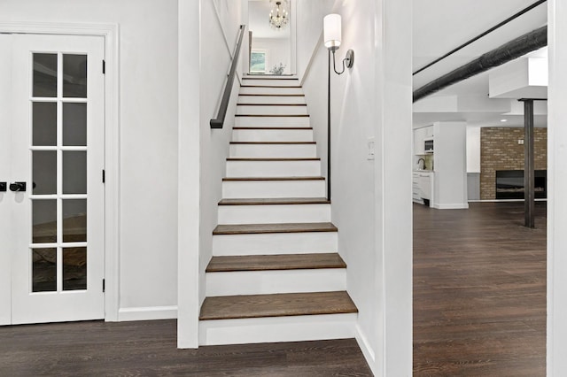 staircase featuring wood-type flooring and a brick fireplace