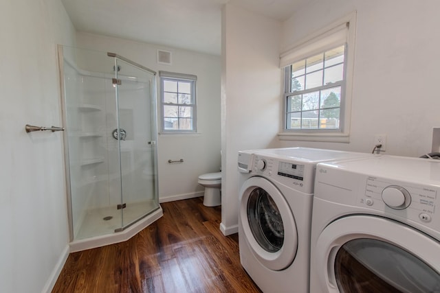 clothes washing area with plenty of natural light, separate washer and dryer, and dark wood-type flooring