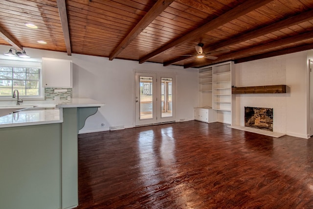 unfurnished living room with beamed ceiling, dark hardwood / wood-style flooring, ceiling fan, and wood ceiling