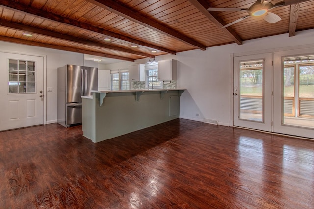 unfurnished living room with wood ceiling, ceiling fan, beamed ceiling, and dark wood-type flooring