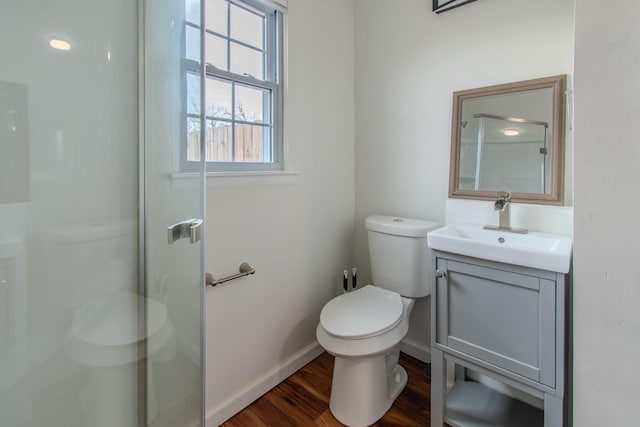 bathroom with a shower with door, vanity, wood-type flooring, and toilet