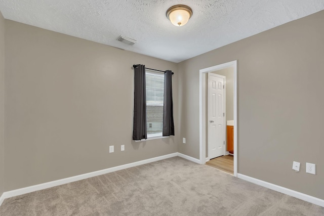 empty room featuring a textured ceiling and light carpet