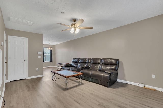 living room featuring hardwood / wood-style flooring, ceiling fan, and a textured ceiling