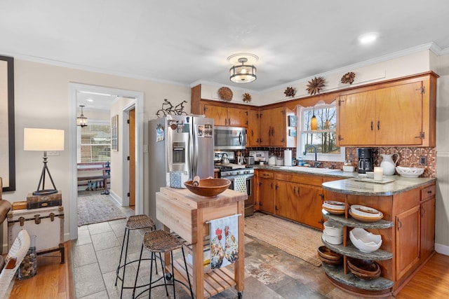 kitchen with appliances with stainless steel finishes, tasteful backsplash, crown molding, and sink