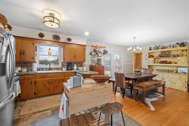 kitchen featuring backsplash, sink, decorative light fixtures, a chandelier, and stainless steel fridge with ice dispenser