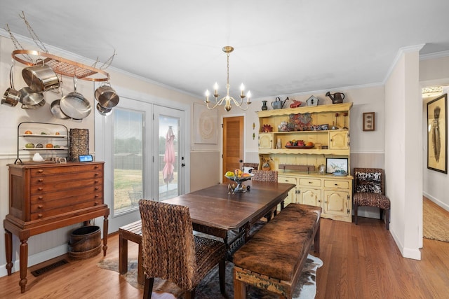 dining area featuring hardwood / wood-style floors, an inviting chandelier, and ornamental molding