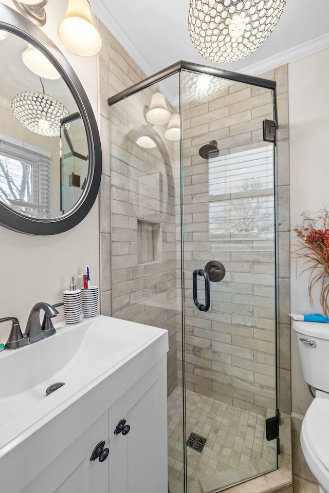 bathroom featuring a shower with shower door, toilet, ornamental molding, and vanity