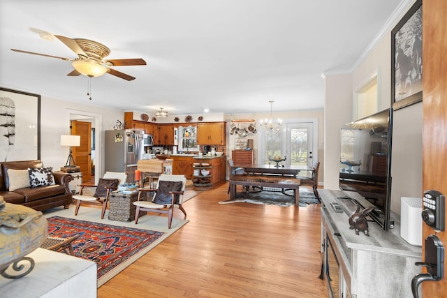 living room with ceiling fan with notable chandelier, light wood-type flooring, and crown molding