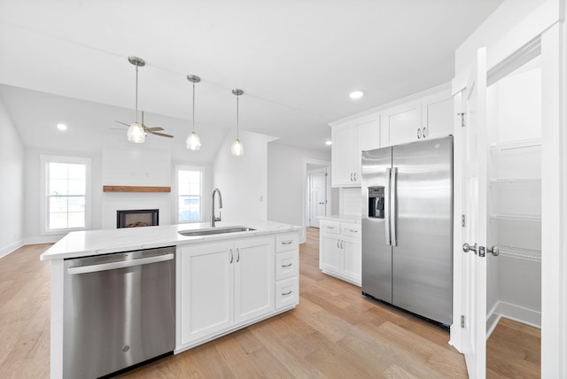 kitchen with an island with sink, stainless steel appliances, sink, and white cabinets