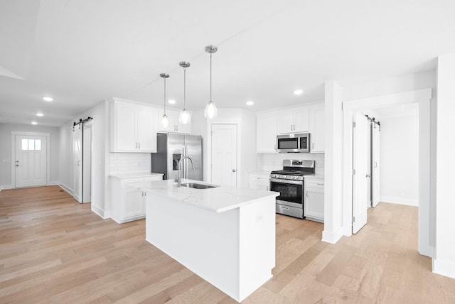 kitchen featuring white cabinetry, a barn door, and appliances with stainless steel finishes