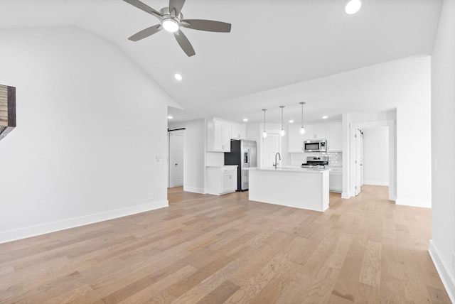 unfurnished living room with ceiling fan, sink, vaulted ceiling, and light hardwood / wood-style flooring