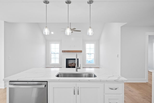 kitchen with stainless steel dishwasher, a healthy amount of sunlight, sink, and white cabinets