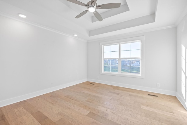 spare room featuring crown molding, light hardwood / wood-style flooring, ceiling fan, and a tray ceiling